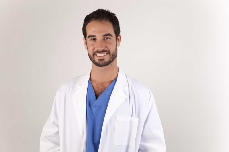 Dr. Sergio Calleja wearing scrubs and a white coat